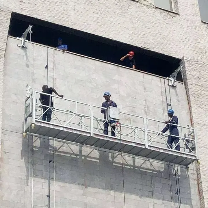 Équipe au travail sur une nacelle suspendue en façade